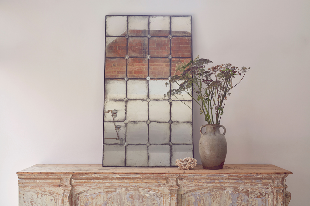 Antique Venetian glass aged mirror from Home Barn reflects light in a neutral interior
