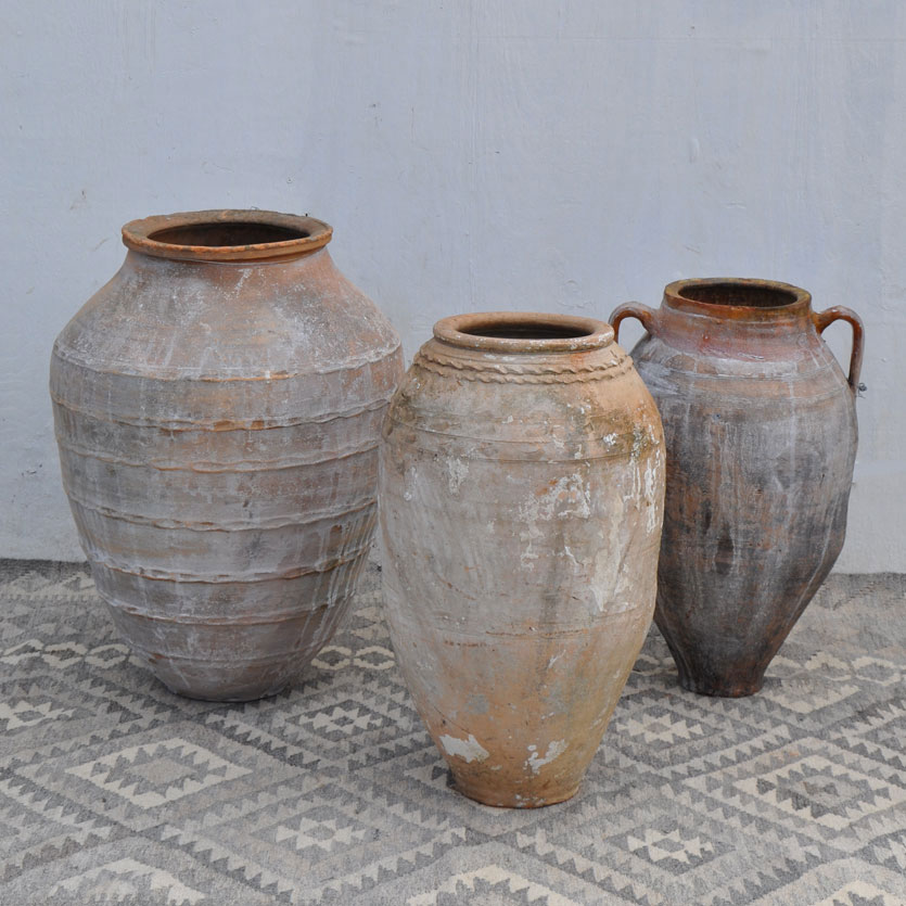 Sculptural antique terracotta pots from the Mediterranean sit on top of a traditional hand-woven kilim rug