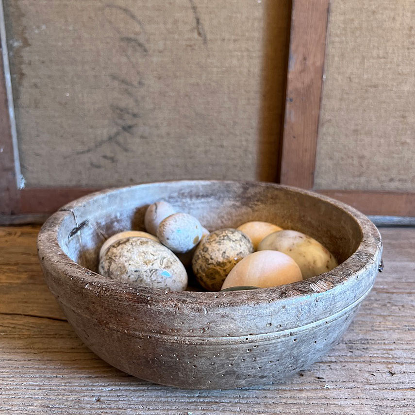 Group of stone eggs in antique bowl